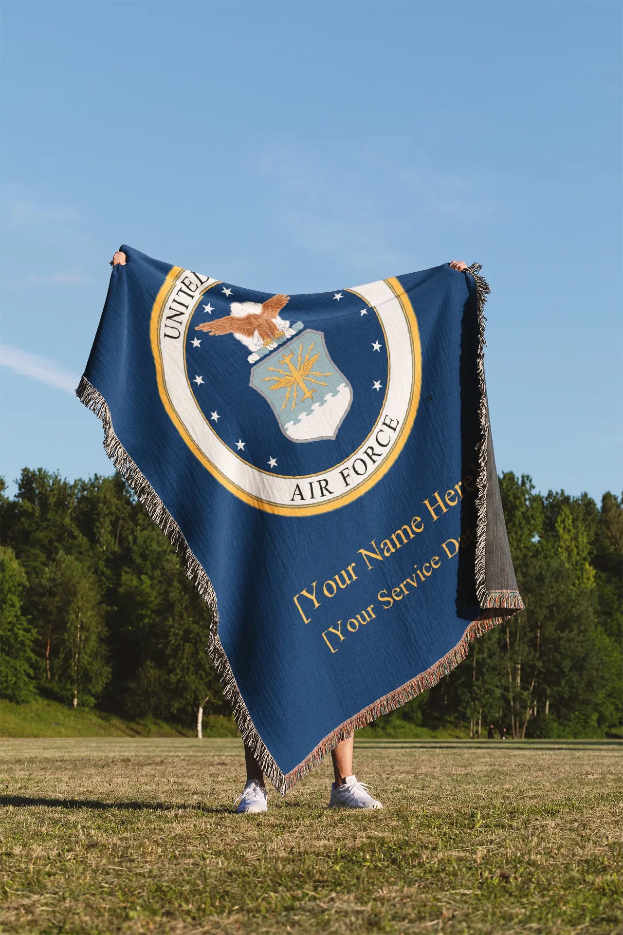  Person standing in a grass field holding a blanket with the Air Force emblem with solid gold text for customer name and service dates on a blue background